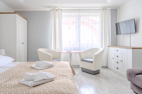 a white bedroom with a bed and a table and chairs at Pablo in Niechorze
