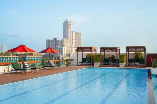 a swimming pool with chairs and umbrellas on a building at Shama Petchburi 47 Bangkok in Bangkok