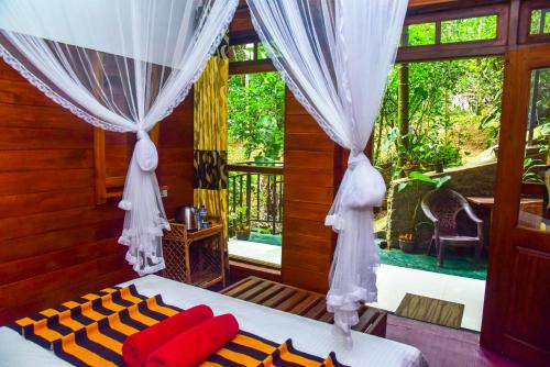 a bedroom with a bed with red pillows and a window at MUM Jungle Inn in Ella