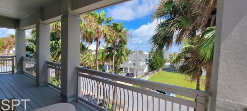 a balcony with a view of a house with palm trees at Luxury Remodel - Sleeps 20 - Pool - Go VIP in South Padre Island