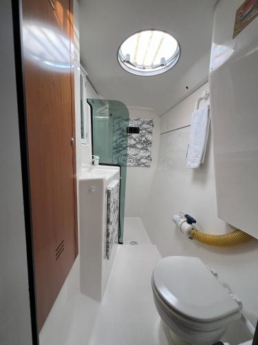 a bathroom with a toilet and a sink and a window at Catamaran Corto Maltese III in Lisbon