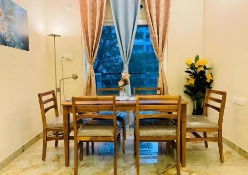 a dining room table with chairs and a window at Evara Bliss - 3BHK Apartment Near Hitec City in Hyderabad