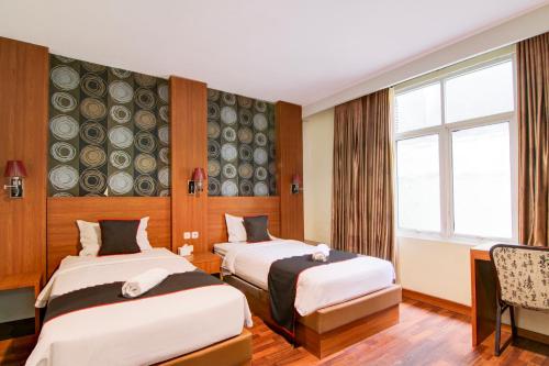 プカンバルにあるCollection O Stefani City Hotelのベッドが2つと窓があるホテルの部屋