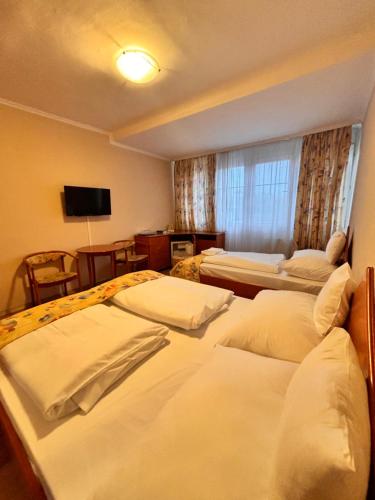 a hotel room with three beds and a television at Hotel Rudolf in Hajdúszoboszló