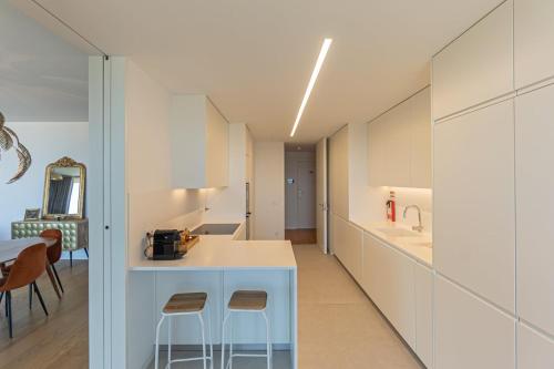 a kitchen with white cabinets and a counter and stools at GuestReady - Urban luxury with Douro view in Vila Nova de Gaia