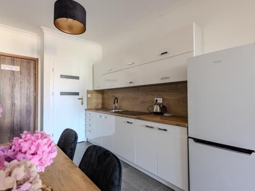 a kitchen with white cabinets and a table with pink flowers at The Old Townhouse III in Krosno