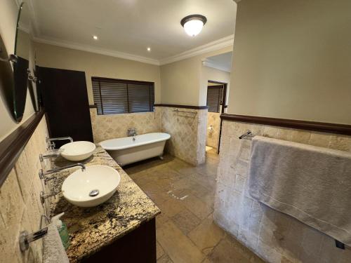 a bathroom with a tub and a sink and a bath tub at Stay Nest Guesthouse in Chartwell