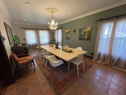 a dining room with a table and chairs and a chandelier at Stay Nest Guesthouse in Chartwell
