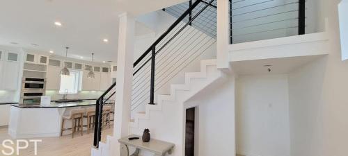 a white staircase in a white kitchen with a table at Luxury Remodel - Sleeps 20 - Pool - Go VIP in South Padre Island