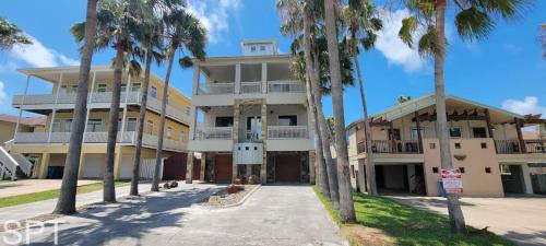 a large building with palm trees in front of it at Luxury Remodel - Sleeps 20 - Pool - Go VIP in South Padre Island