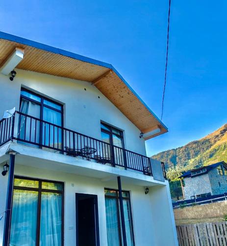 a white house with a balcony on top of it at Hillside Mestia ჰილსაიდ მესტია in Mestia