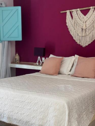 a bedroom with a white bed with a purple wall at Pousada Ilha do Vento in São Miguel do Gostoso