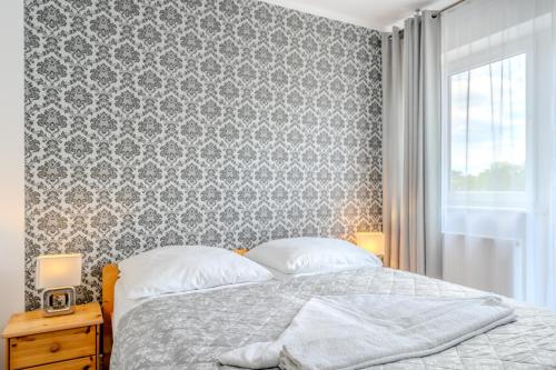 a bedroom with a bed with a damask wallpaper at Pablo in Niechorze