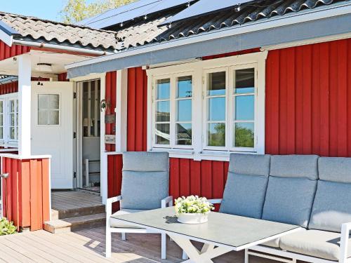 a red house with chairs and a table on a deck at 6 person holiday home in Slöinge in Slöinge