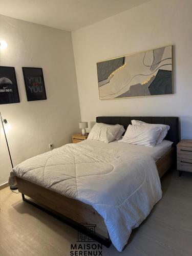 une chambre avec un grand lit aux draps blancs dans l'établissement Maison Serenux, à Douala