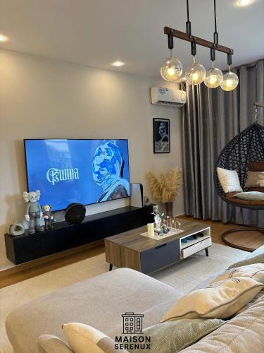 un salon avec une télévision grand écran dans l'établissement Maison Serenux, à Douala