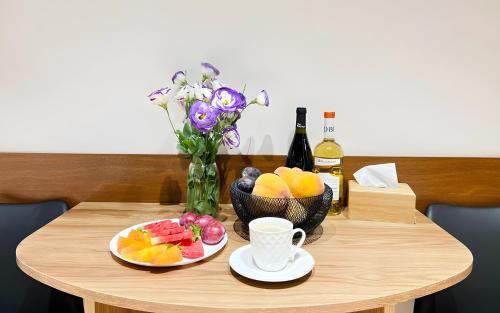 a table with plates of fruit and a vase of flowers at Rooms Apart Hotel by RED in Yerevan