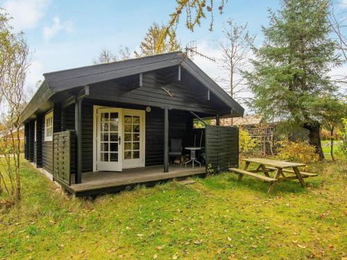 a black cabin with a picnic table in the grass at 4 person holiday home in Fårvang-By Traum in Fårvang