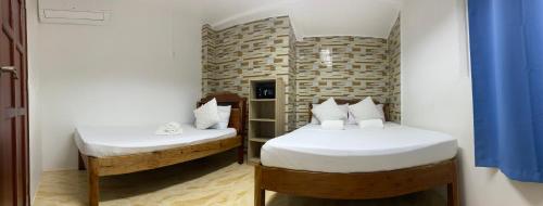 two twin beds in a room with blue curtains at A&C Aquino Guesthouse in Moalboal