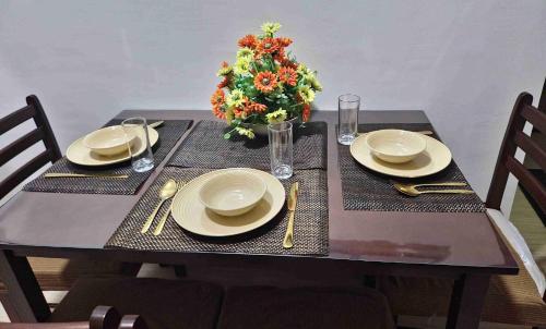 a table with plates and a vase of flowers on it at Colins Suite at Hope Residences in Trece Martires