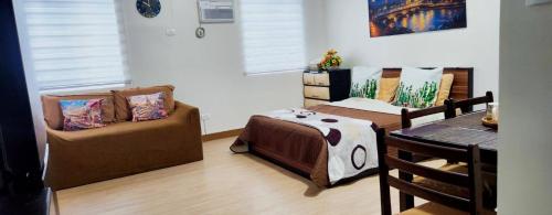 a room with two beds and a couch and a table at Colins Suite at Hope Residences in Trece Martires