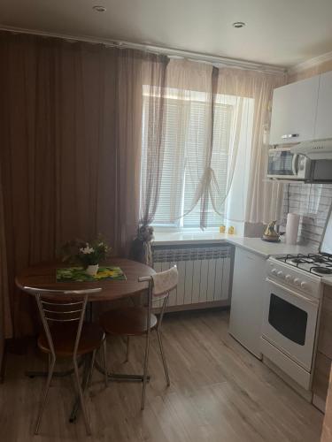 a kitchen with a table with chairs and a stove at Apartment on Artyleriiska 2 with River View in Mykolaiv