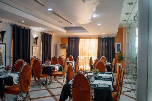 a dining room with tables and chairs and a room withwindows at Morning Side Suites in Lagos