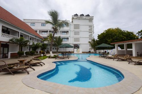 a pool at a hotel with chairs and a building at The Safiya Hotel, Diani Beach in Diani Beach