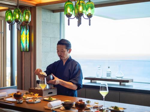 a man preparing food at a table in a restaurant at UMITO Atami Bettei in Atami