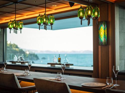 a restaurant with tables and chairs and a view of the ocean at UMITO Atami Bettei in Atami