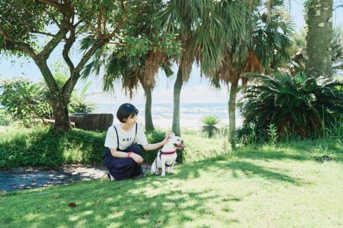 a woman petting a small dog in a park at 1NLDK hyuga in Hyuga
