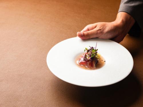 a person holding a white plate with a piece of food at UMITO Atami Bettei in Atami