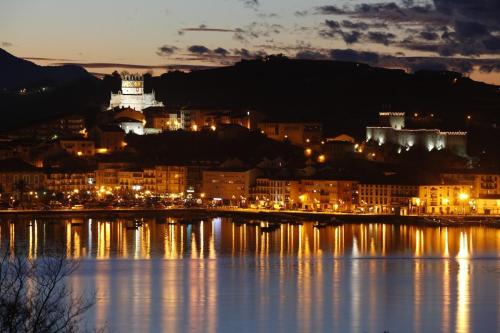 a city lit up at night next to a body of water at Casa Taro San Vicente de la Barquera in San Vicente de la Barquera