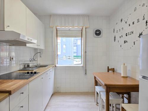 a white kitchen with a table and a window at Casa Taro San Vicente de la Barquera in San Vicente de la Barquera
