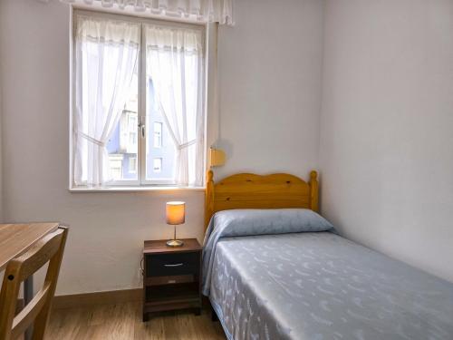 a small bedroom with a bed and a window at Casa Taro San Vicente de la Barquera in San Vicente de la Barquera