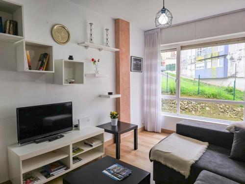 a living room with a couch and a tv and a window at Casa Taro San Vicente de la Barquera in San Vicente de la Barquera