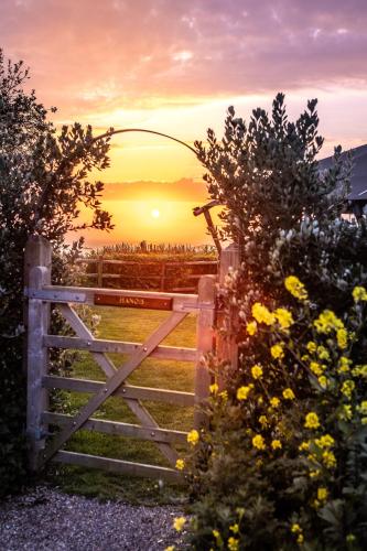 a gate to a field with a sunset behind it at Luxury Glampsite with Sea Views in St Peter