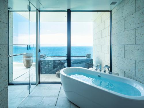 a bath tub in a bathroom with a view of the ocean at UMITO Atami Bettei in Atami
