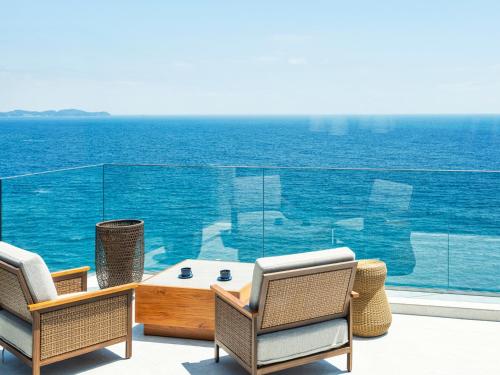 a patio with chairs and a table and the ocean at UMITO Atami Bettei in Atami