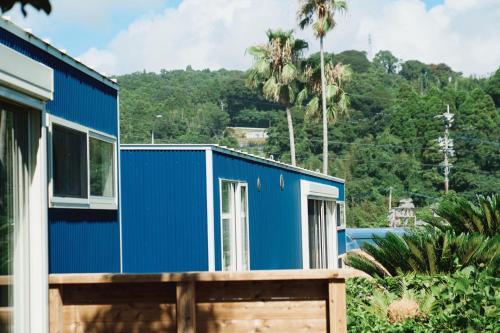 a blue tiny house with a mountain in the background at 1NLDK hyuga in Hyuga