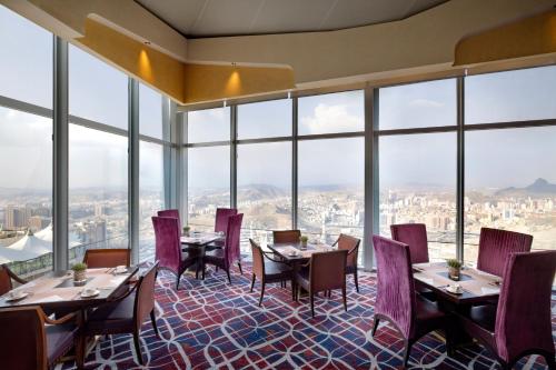 a restaurant with tables and chairs and large windows at Makkah Clock Royal Tower, A Fairmont Hotel in Makkah