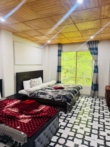 a bedroom with two beds and a large window at Green view guest house nathiagali by room in Nathia Gali