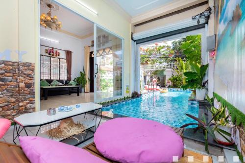 a room with a pool and a table and pink chairs at Villages Hồ Bơi Võ Thị Sáu Lô Góc gần Quảng Trường in Vung Tau