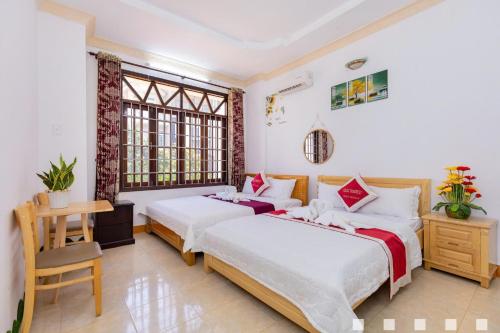 a bedroom with two beds and a desk and windows at Villages Hồ Bơi Võ Thị Sáu Lô Góc gần Quảng Trường in Vung Tau