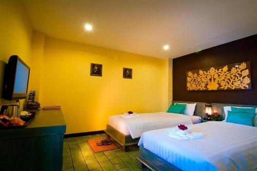 a hotel room with two beds and a flat screen tv at CM Night Bazaar Boutique Hotel - โรงแรม ซี เอ็ม ไนท์บาซาร์ บูทีค in Chiang Mai
