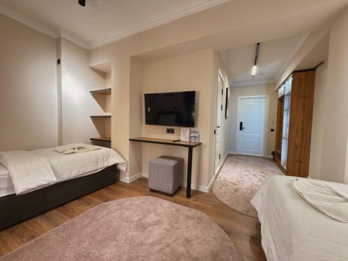 a bedroom with two beds and a desk with a tv at Status Inn Hotel in Samarkand