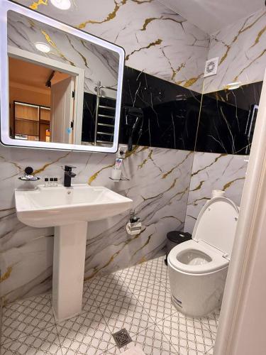 a bathroom with a sink and a toilet and a mirror at Status Inn Hotel in Samarkand