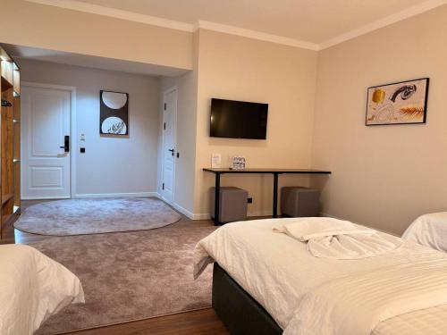 a bedroom with two beds and a desk and a television at Status Inn Hotel in Samarkand