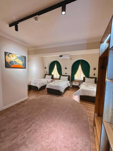 a large room with three beds and a rug at Status Inn Hotel in Samarkand