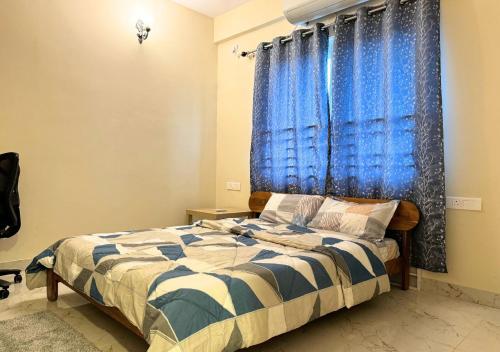 a bedroom with a bed and a blue curtain at Evara Grand Vista - Fully Equipped 3BHK near AMB in Hyderabad